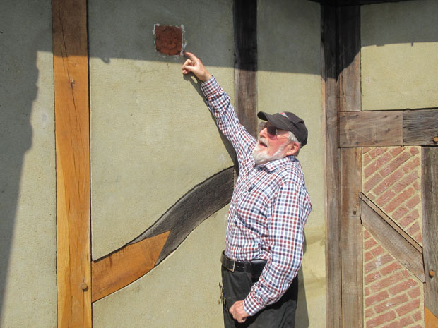 Mike Jordan, former chair of Barnet Museum trustees, pointing to one of the early tiles in the mock-Tudor façade of Barnet Physic Well.